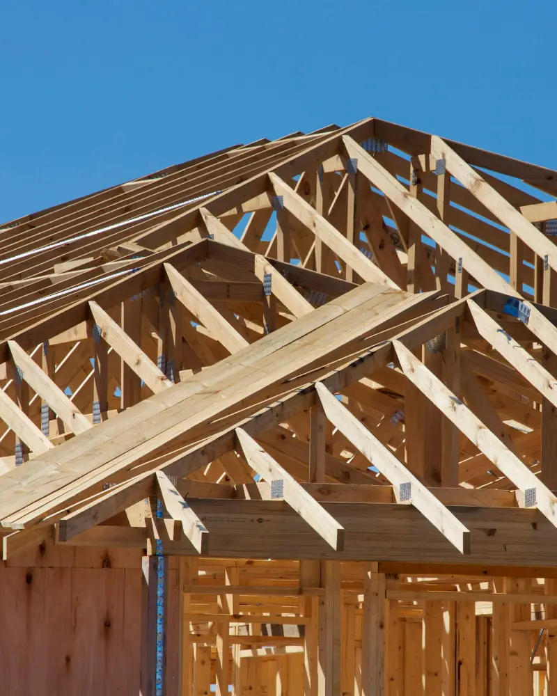 Houten kapconstructie van een nieuw huis tegen een blauwe lucht
