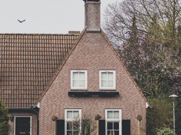 Vrijstaande woning van rode baksteen met een steil pannendak en een schoorsteen