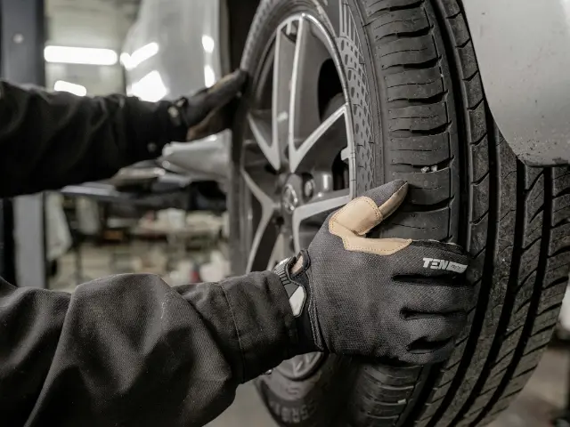 Monteur zet een wiel met nieuwe band op de auto