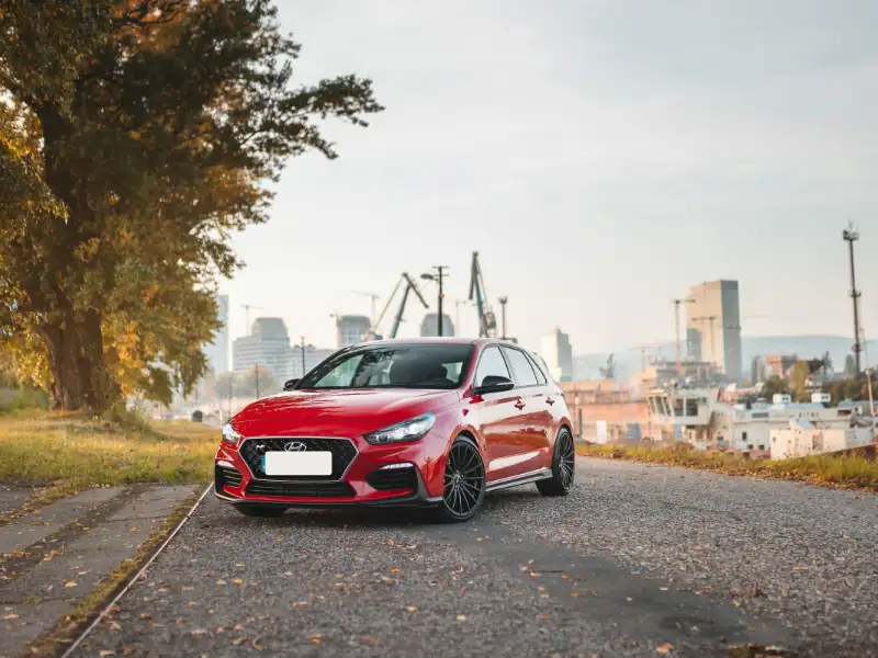 Rode Hyundai i30 op een kade met hijskranen op de achtergrond