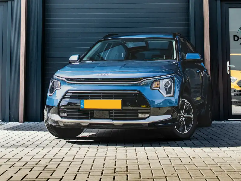 Blauwe Kia Niro EV voor een donkere garagedeur