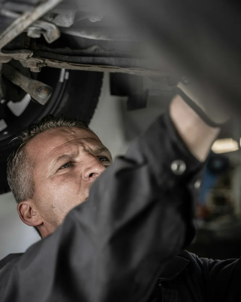 Sjoerd kijkt met een lamp onder een auto op de brug