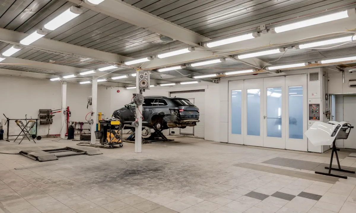 Lichte schadewerkplaats met een auto op de brug en de deuren van de spuitcabine