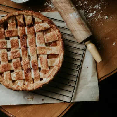 Appeltaart met een rooster van deeg naast een deegroller