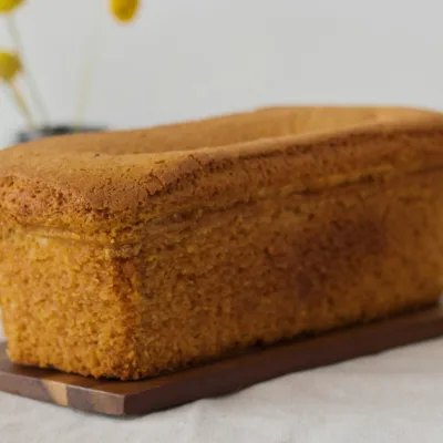 Een donkere koek in broodvorm op een houten plankje