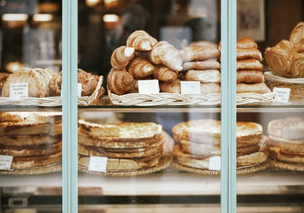 Een toonbank met vitrines vol brood en gebak in een lichte winkel
