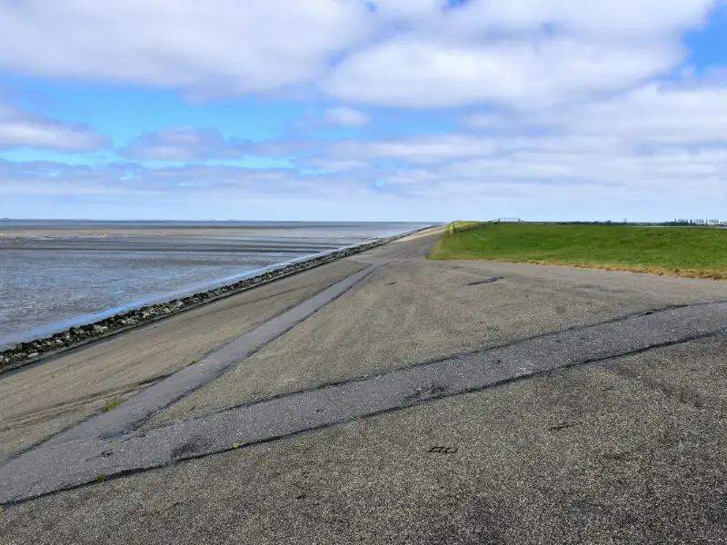 De zeedijk met een fietspad langs het wad onder een wolkenlucht