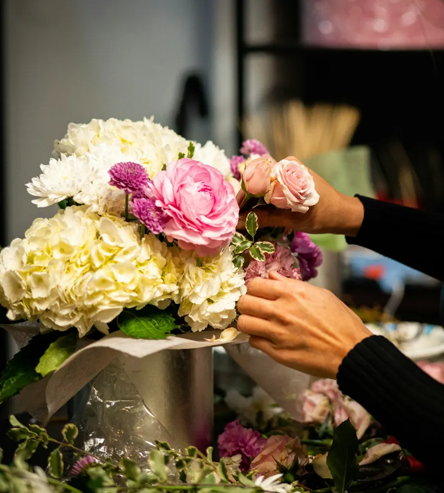 Een bloemist schikt hortensia's en roze rozen in een bloemstuk