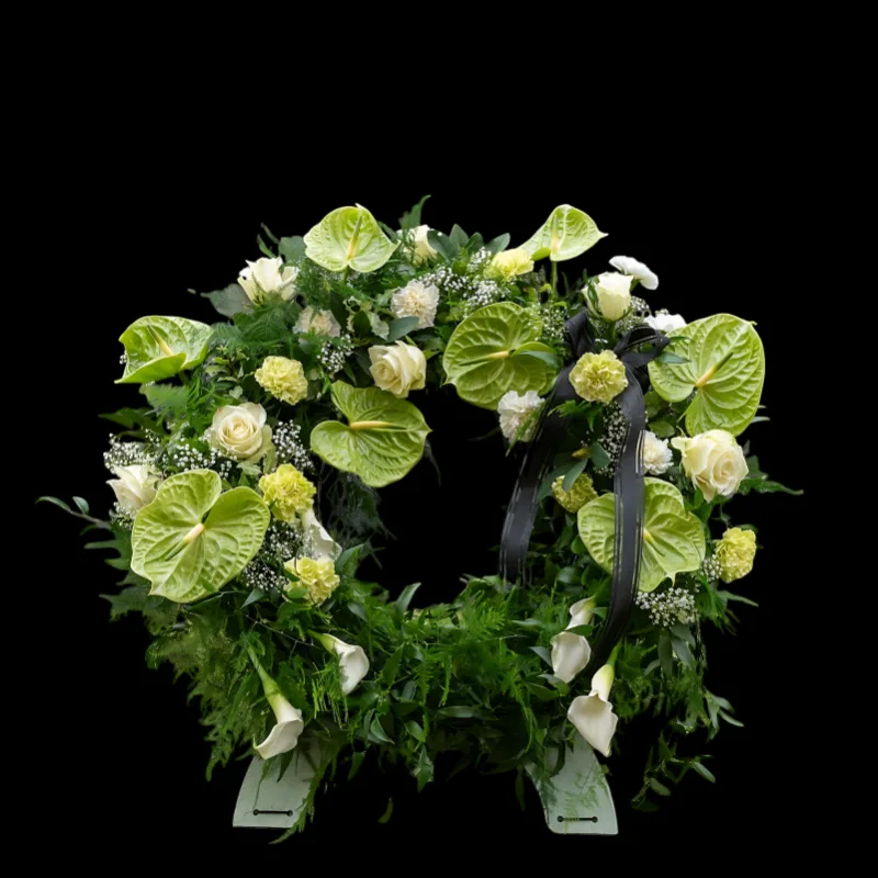 Een ronde krans van witte bloemen, groene anthuriums en blad