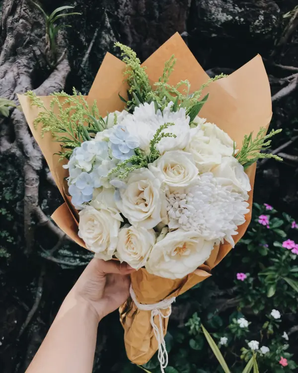 Een boeket witte rozen en hortensia in bruin papier