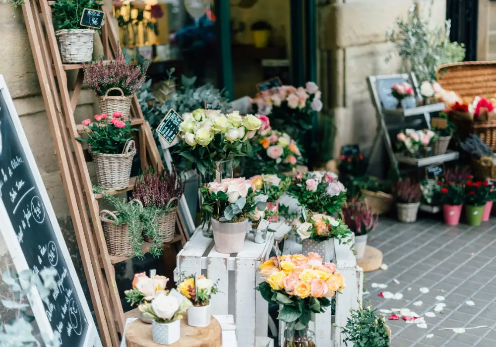 Emmers en kistjes vol bloemen en planten voor de ingang van een bloemenwinkel
