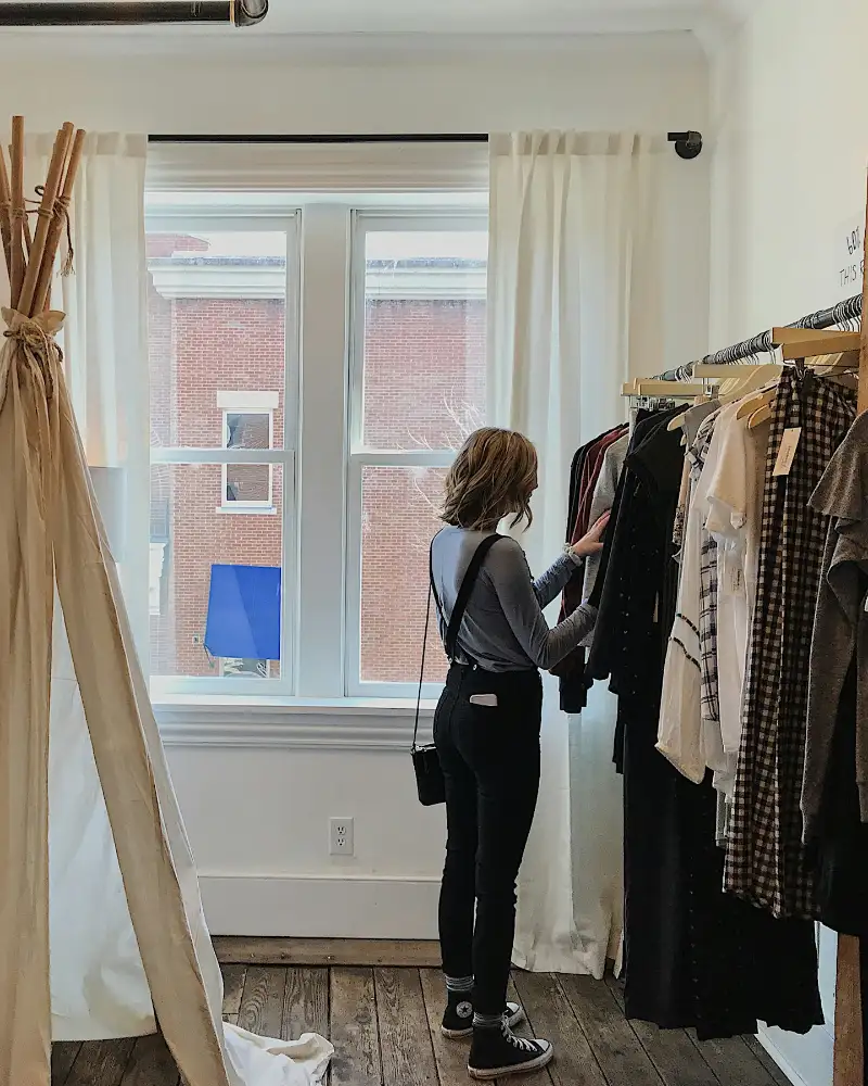 Een vrouw zoekt kleding uit aan een rek in een lichte winkel