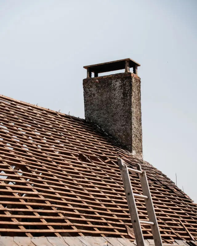 Pannendak met een gemetselde schoorsteen en een ladder tegen de dakrand