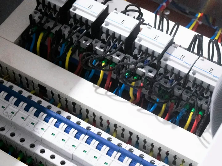 Nieuwe groepenkast met een rij aardlekautomaten en netjes gebundelde blauwe, bruine en geelgroene draden
