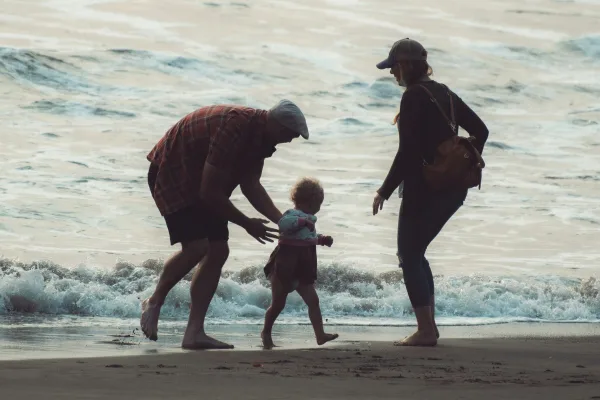 Twee ouders spelen met hun kind in de golven op het strand