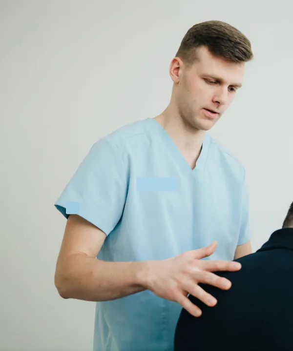 Rients in een lichtblauw praktijkshirt legt zijn hand op de schouder van een patiënt