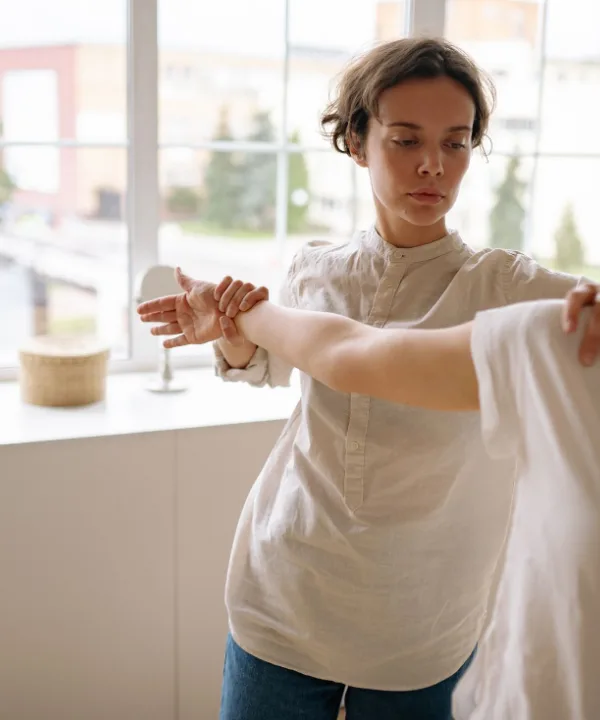 Sjoukje begeleidt bij het raam een vrouw die haar arm strekt