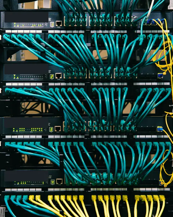 Een netwerkkast met vier switches en strak gebundelde blauwe en gele netwerkkabels