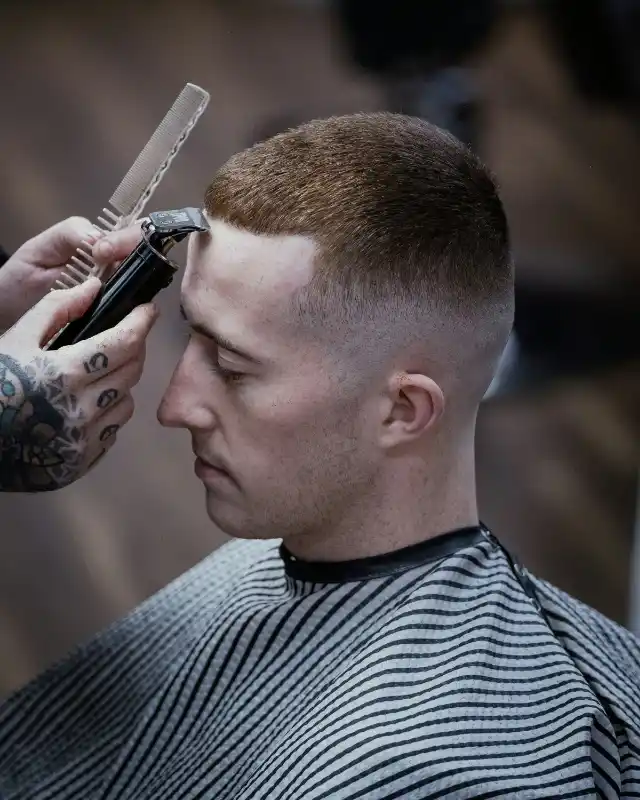 Een barbier knipt een korte fade met tondeuse en kam