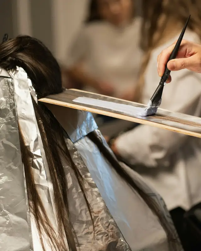 Een kapper zet lokken in folie voor een balayage