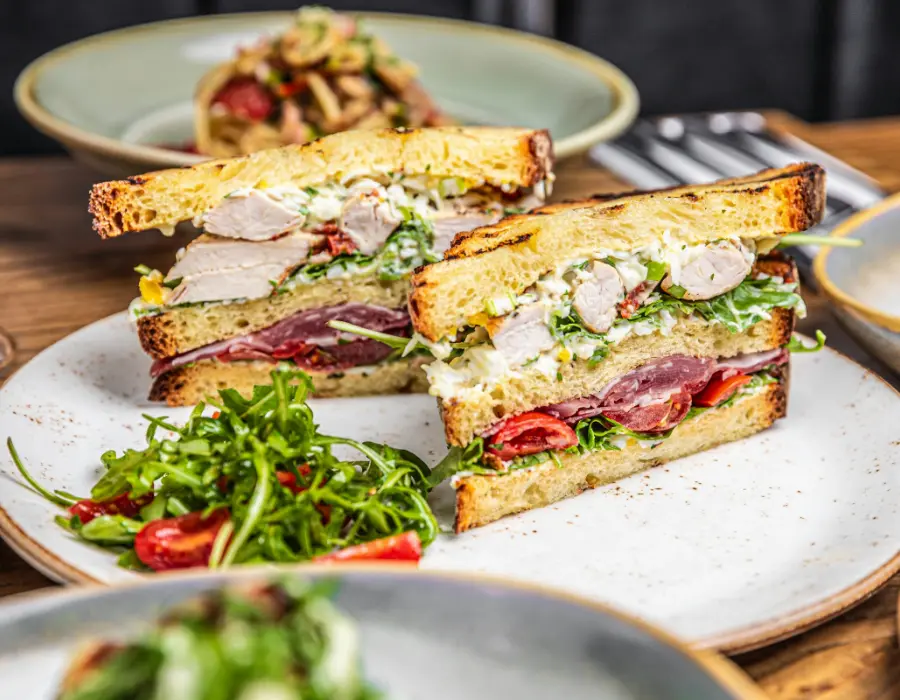 Belegde boterhammen met kip, ham en rucola op witte borden
