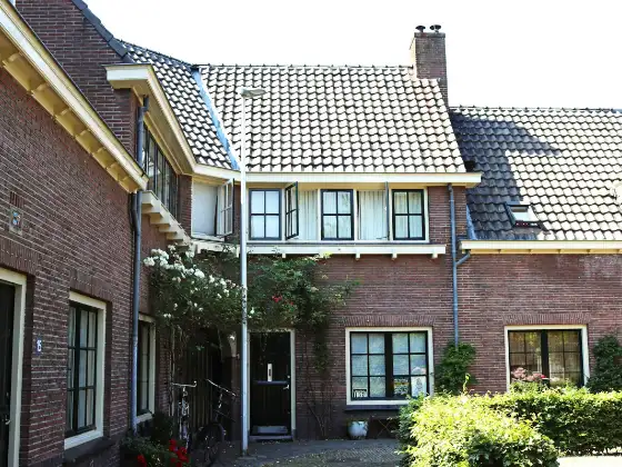 Rij bakstenen jarendertighuizen met witte kozijnen en een voortuin met hortensia's