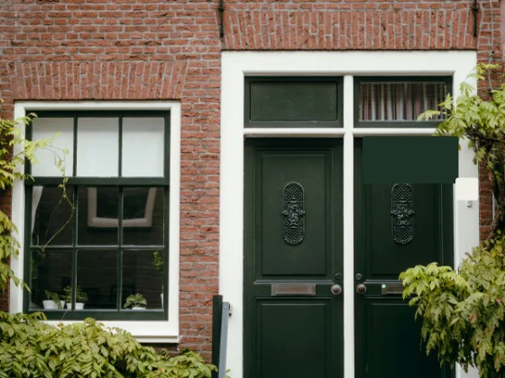 Bakstenen gevel met een groene dubbele voordeur en een raam met groene kozijnen