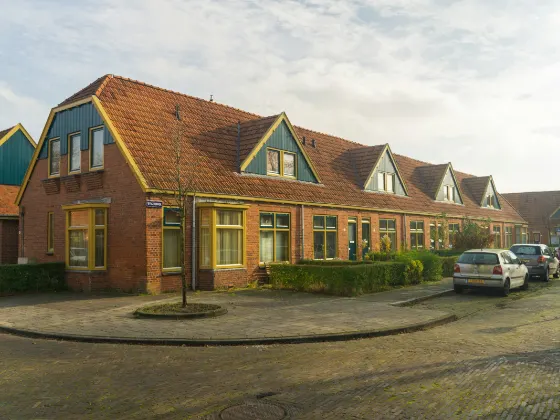 Rij arbeiderswoningen met oranje daken en geel geschilderde kozijnen