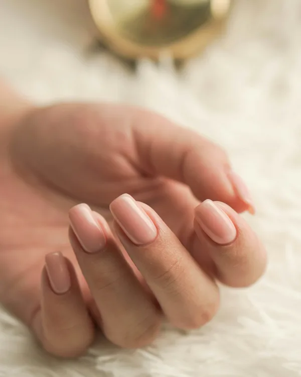 Hand met korte nagels in een zachte, melkachtige nudetint