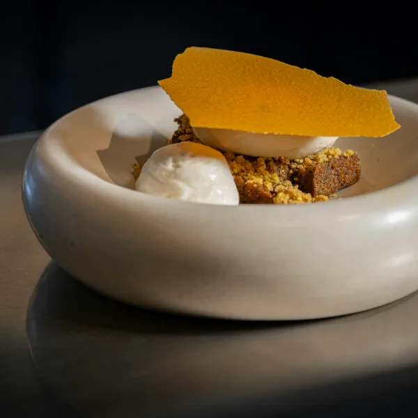 Nagerecht in een witte kom: ijs, kruim en een dunne oranje krokant