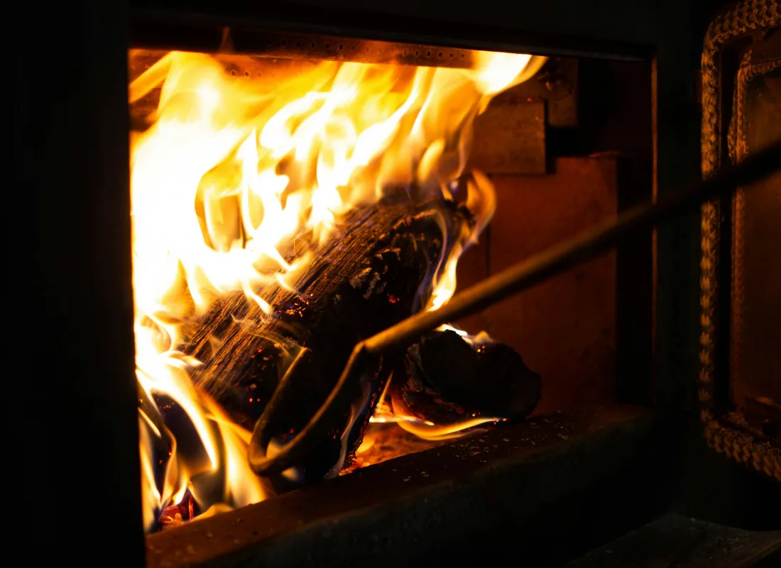 Brandende houtblokken in de oven, met een pook ernaast