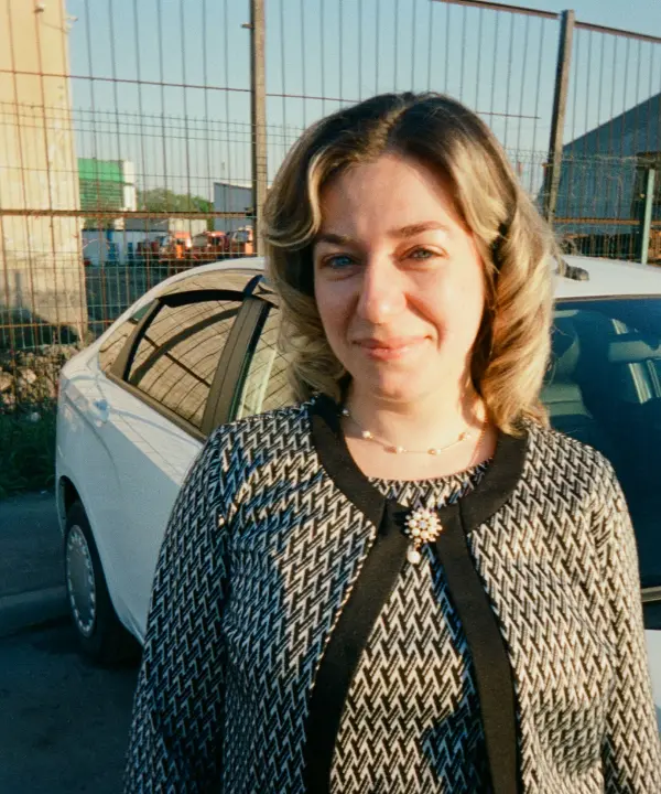 Sietske, eigenaar en instructeur, staat glimlachend voor een witte auto