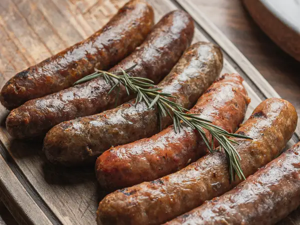 Gegrilde braadworsten met rozemarijn op een plank