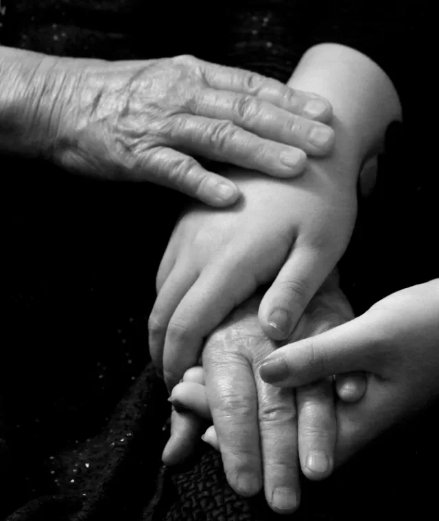Zwart-witfoto van een oude hand die op de handen van een kind rust